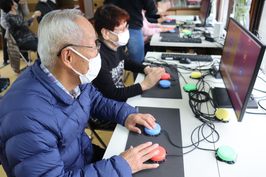 高齢者がUDe-スポーツの画面を見ながら対戦している様子